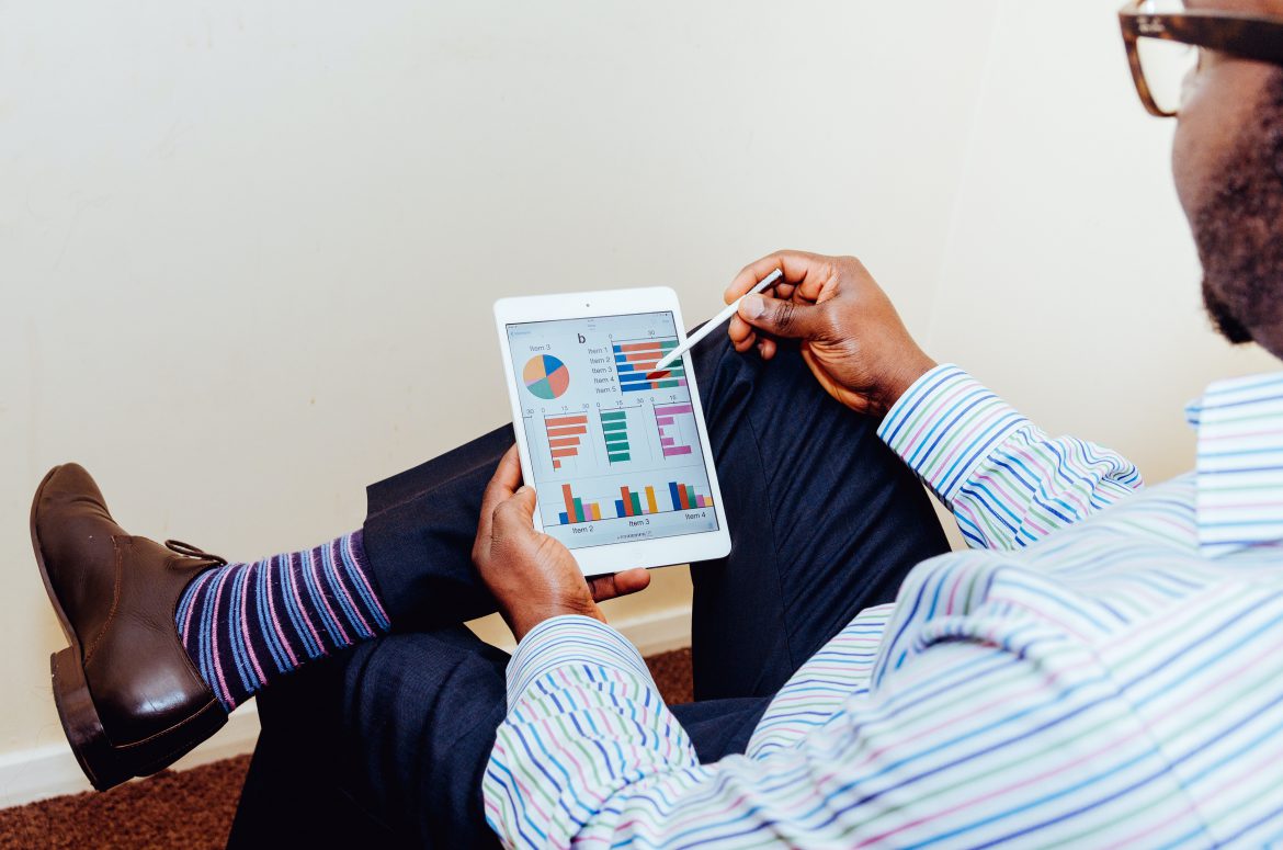 man looking at smartphone and graphs How to track ASO KPIs more effectively